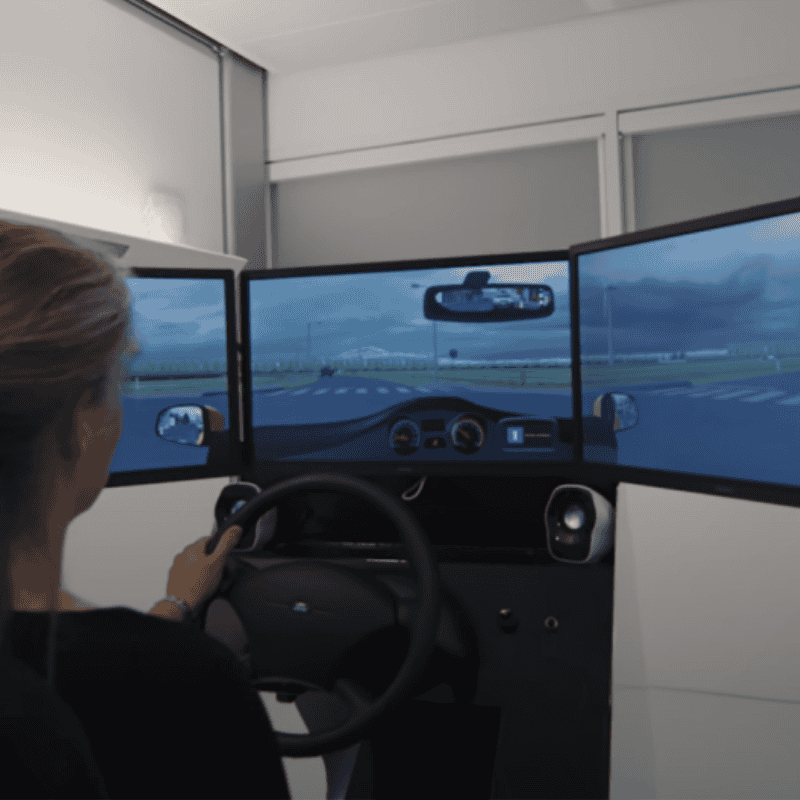 Iemand op een simulator met 3 beeldschermen